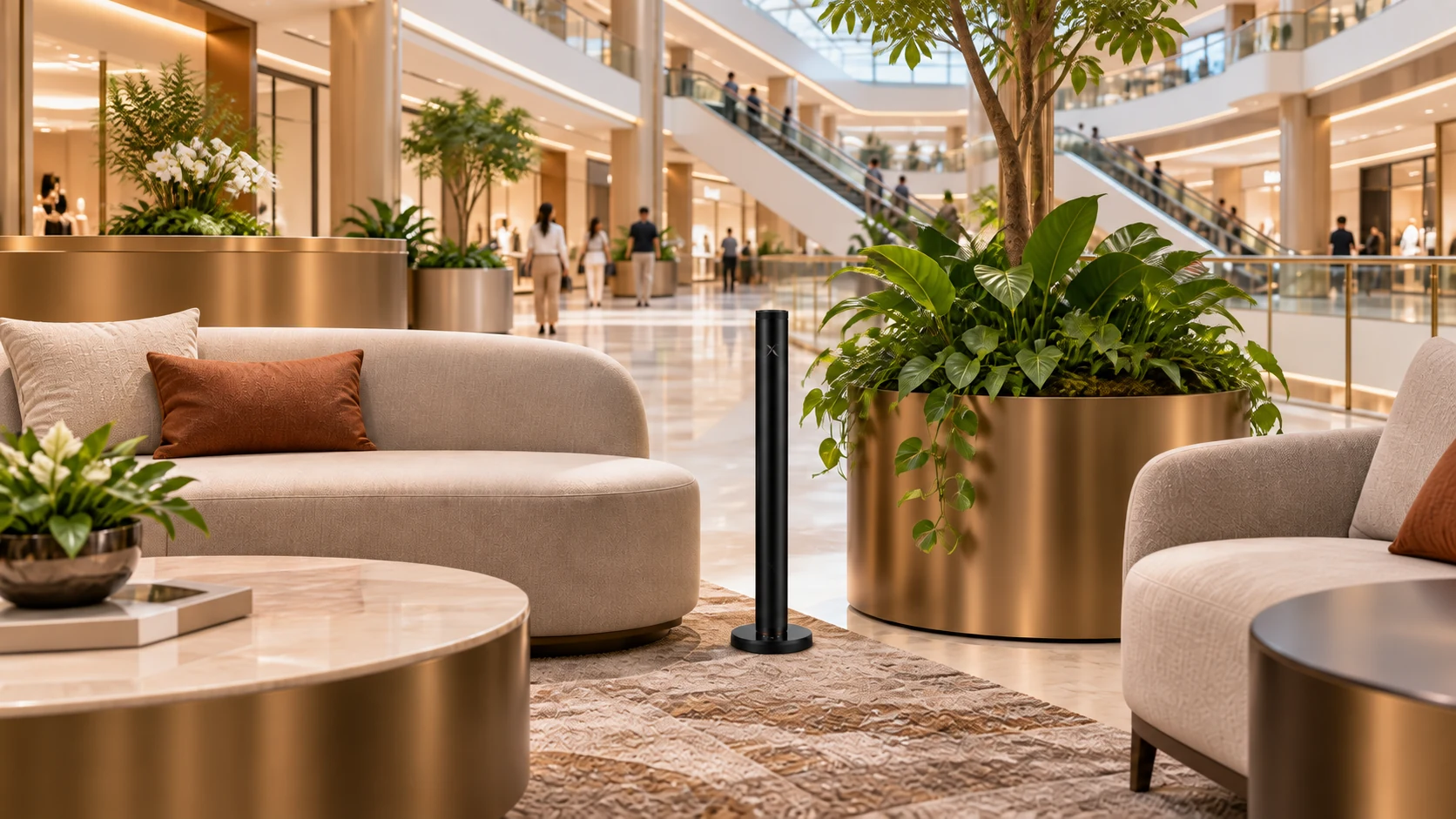 An X AP40 diffuser beside soft lounge seating and bronze planters in a bright shopping-mall atrium, with shoppers and escalators beyond