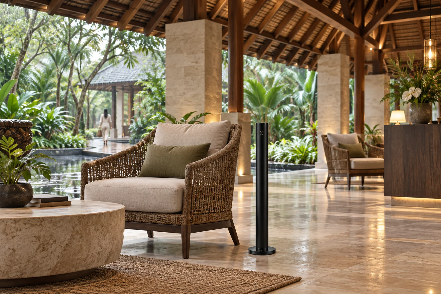 A black X AP40 diffuser beside woven lounge furniture in a tropical resort arrival pavilion overlooking lush gardens