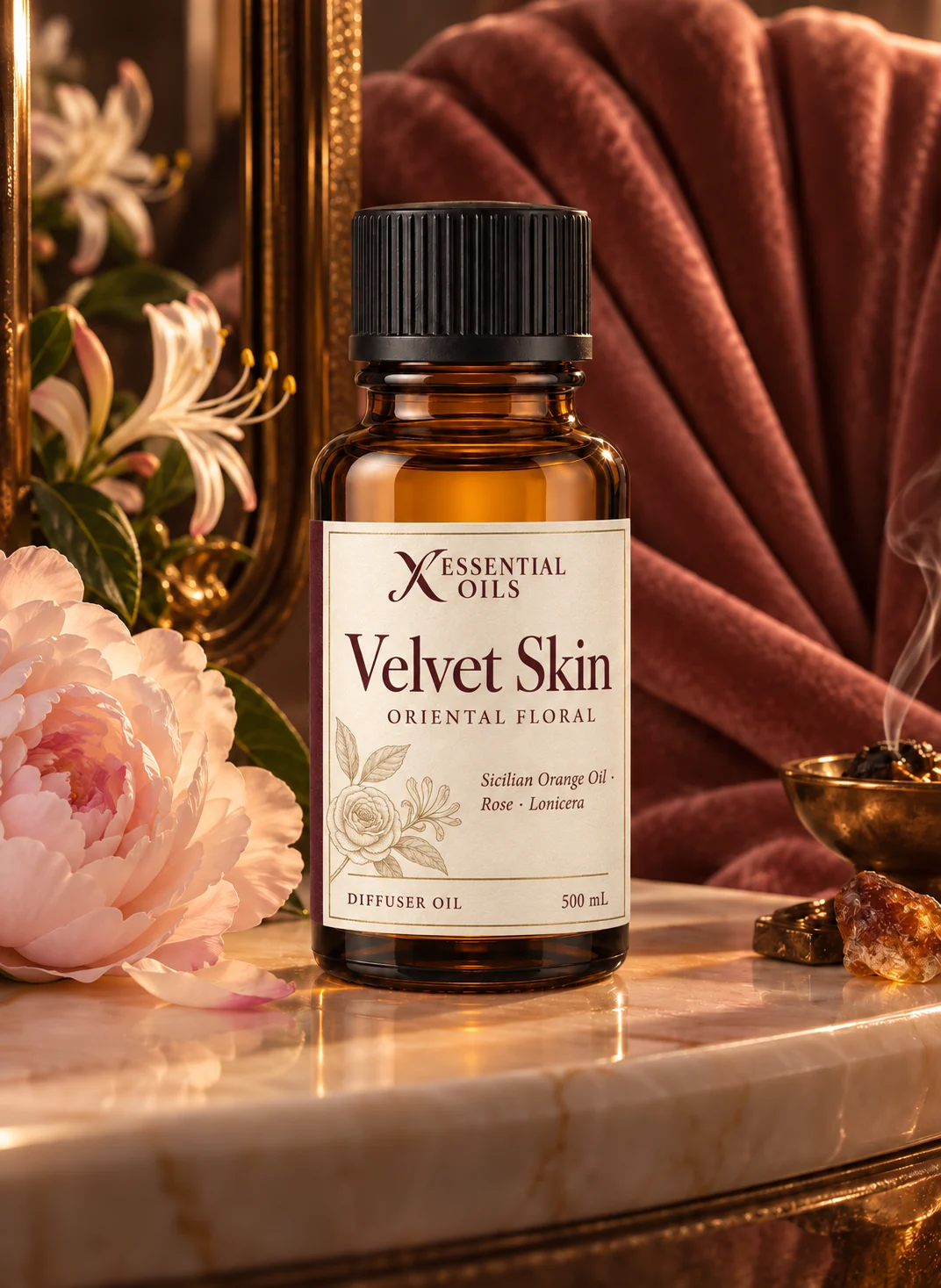 Velvet Skin oil bottle on an alabaster vanity with peach velvet, honeysuckle and a pale peony in warm light.