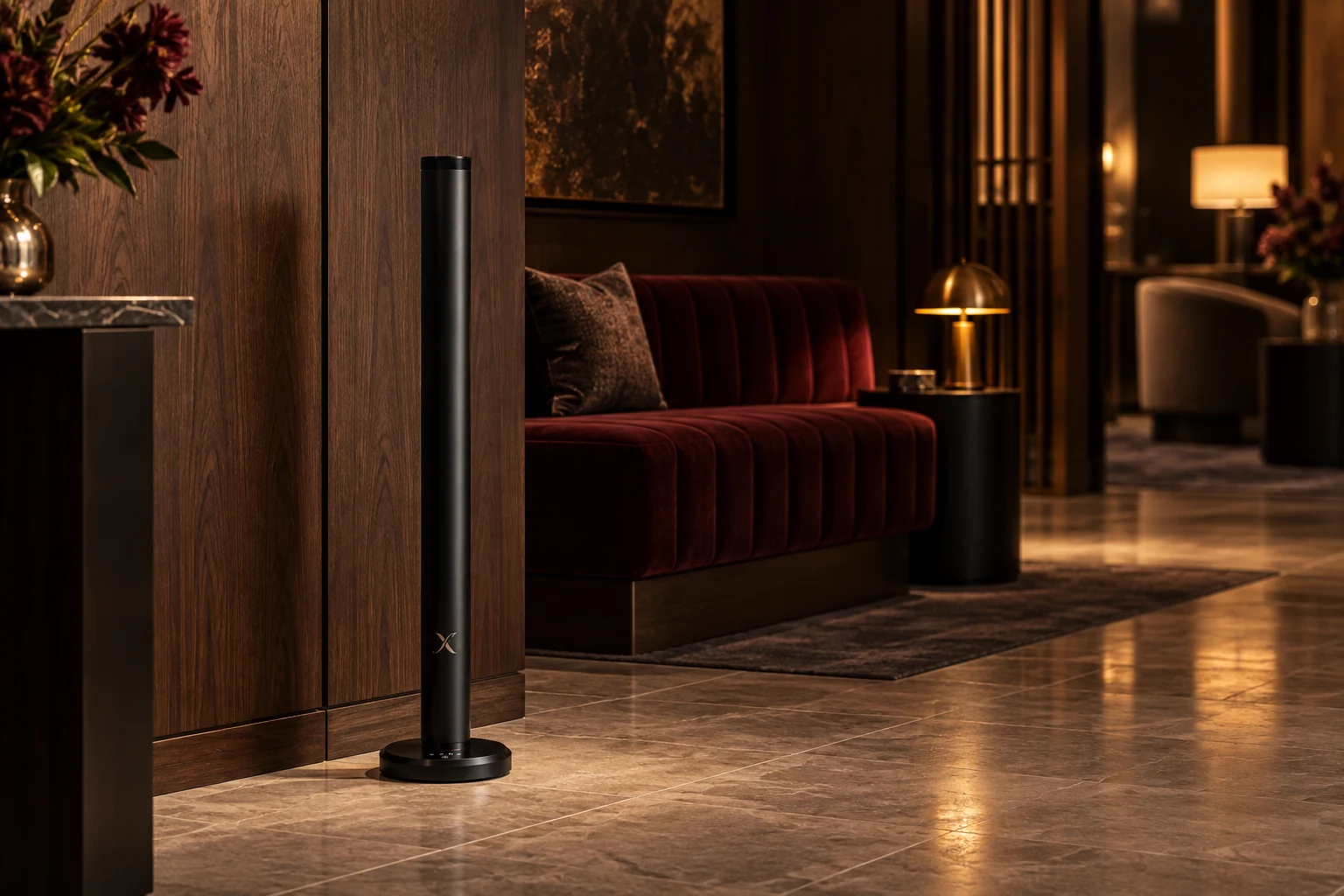A slim black X AP40 diffuser beside a walnut wall and burgundy seating, with a clear route through a warm hotel lounge